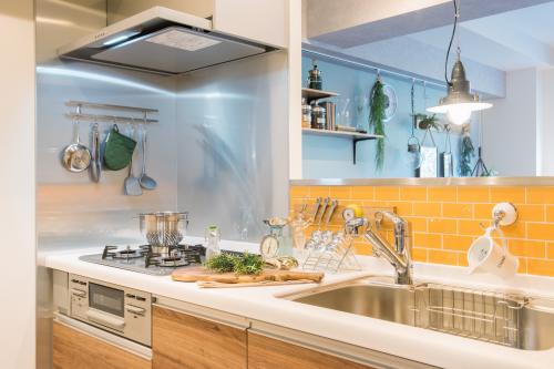 【キッチン】　毎日使うキッチンにはビタミンカラーのタイル、コンロ側壁にはステンレスを採用。オープンキッチンのあるカフェで使用されているキッチンマグネットツールホルダーで、調理器具を飾りながら収納し、使い易さと見栄えを兼ね備えた。